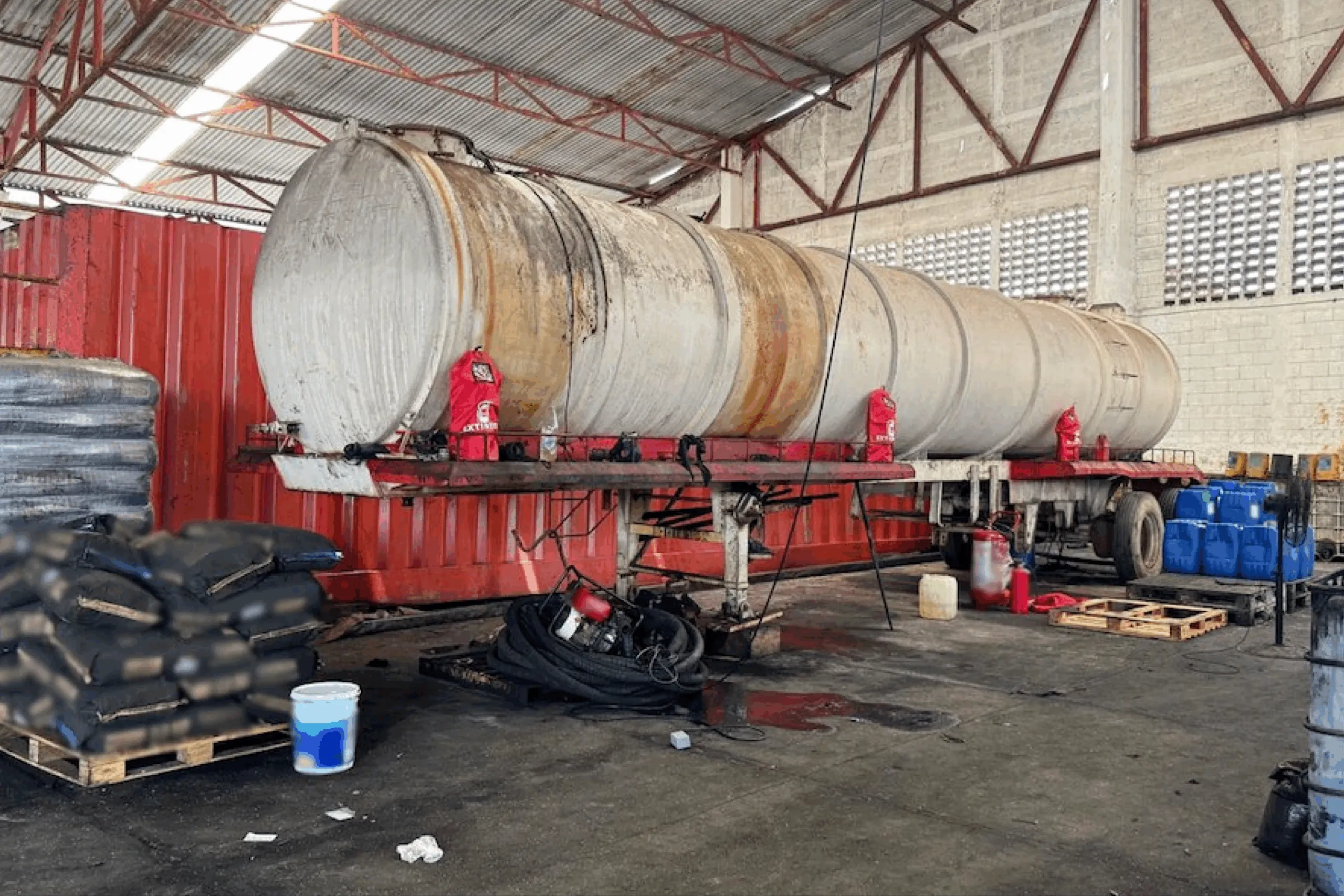 Contenedores de combustible en instalaciones clandestinas controladas por cárteles, utilizados para almacenar huachicol antes de su exportación ilegal a Asia y África, según autoridades de EUA.