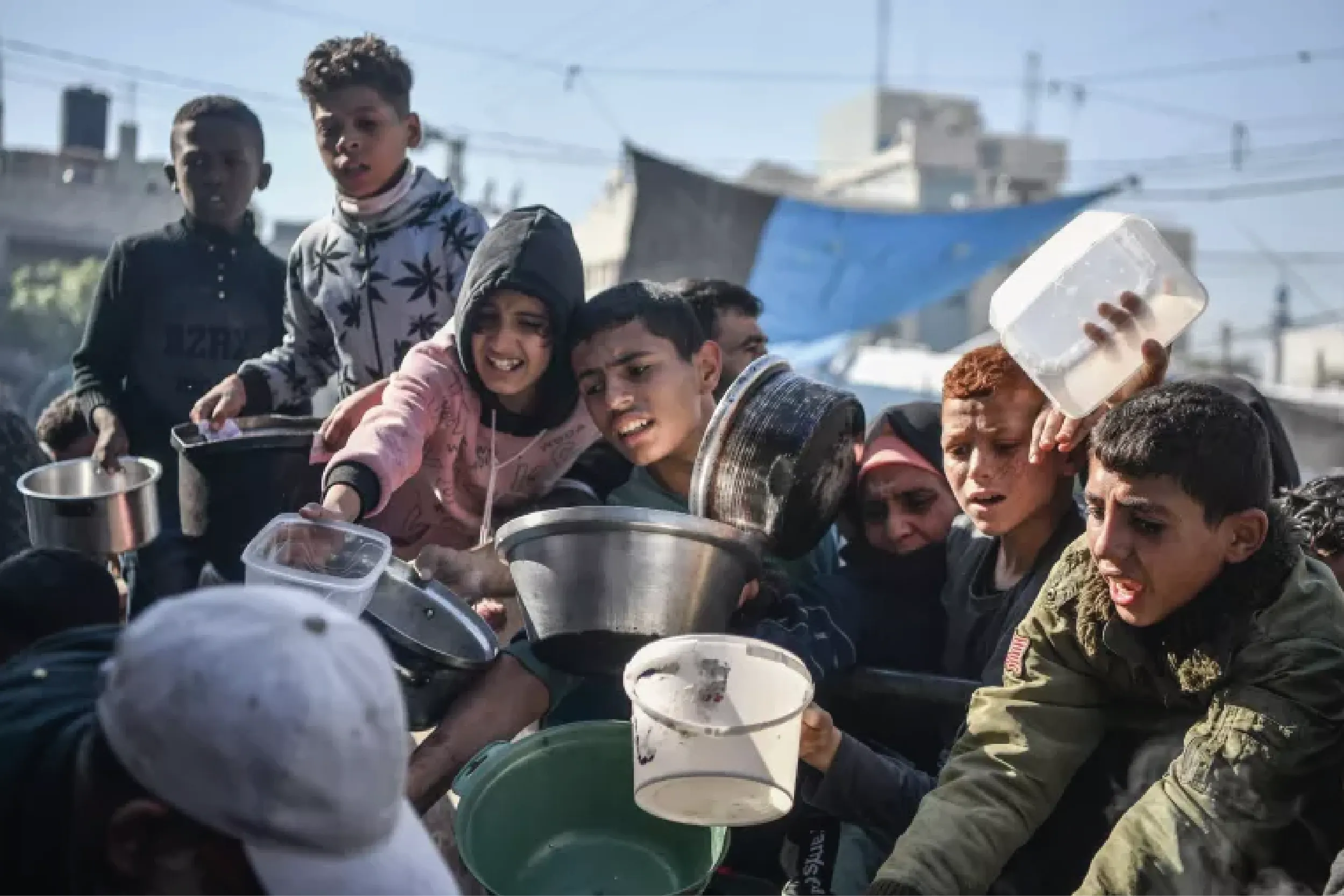 Niños palestinos en Gaza esperan junto a sus familias alimentos de ayuda humanitaria, en medio del asedio y la escasez crítica de recursos. Foto: UNICEF