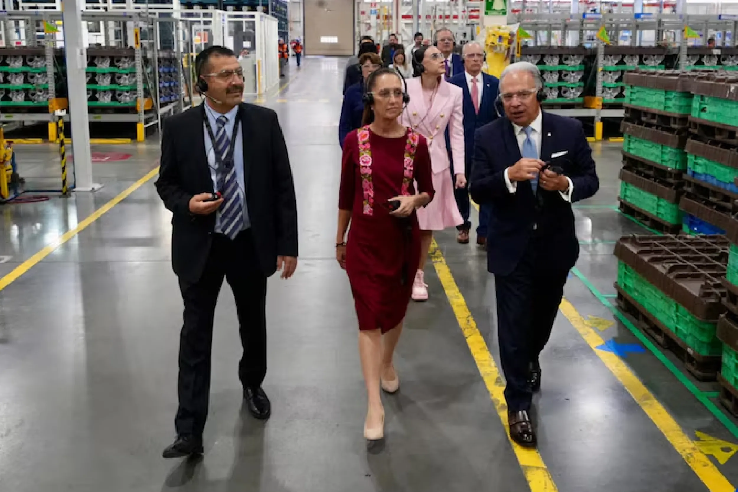 Group of professionals wearing headsets walking through a warehouse aisle, inspecting the facility.