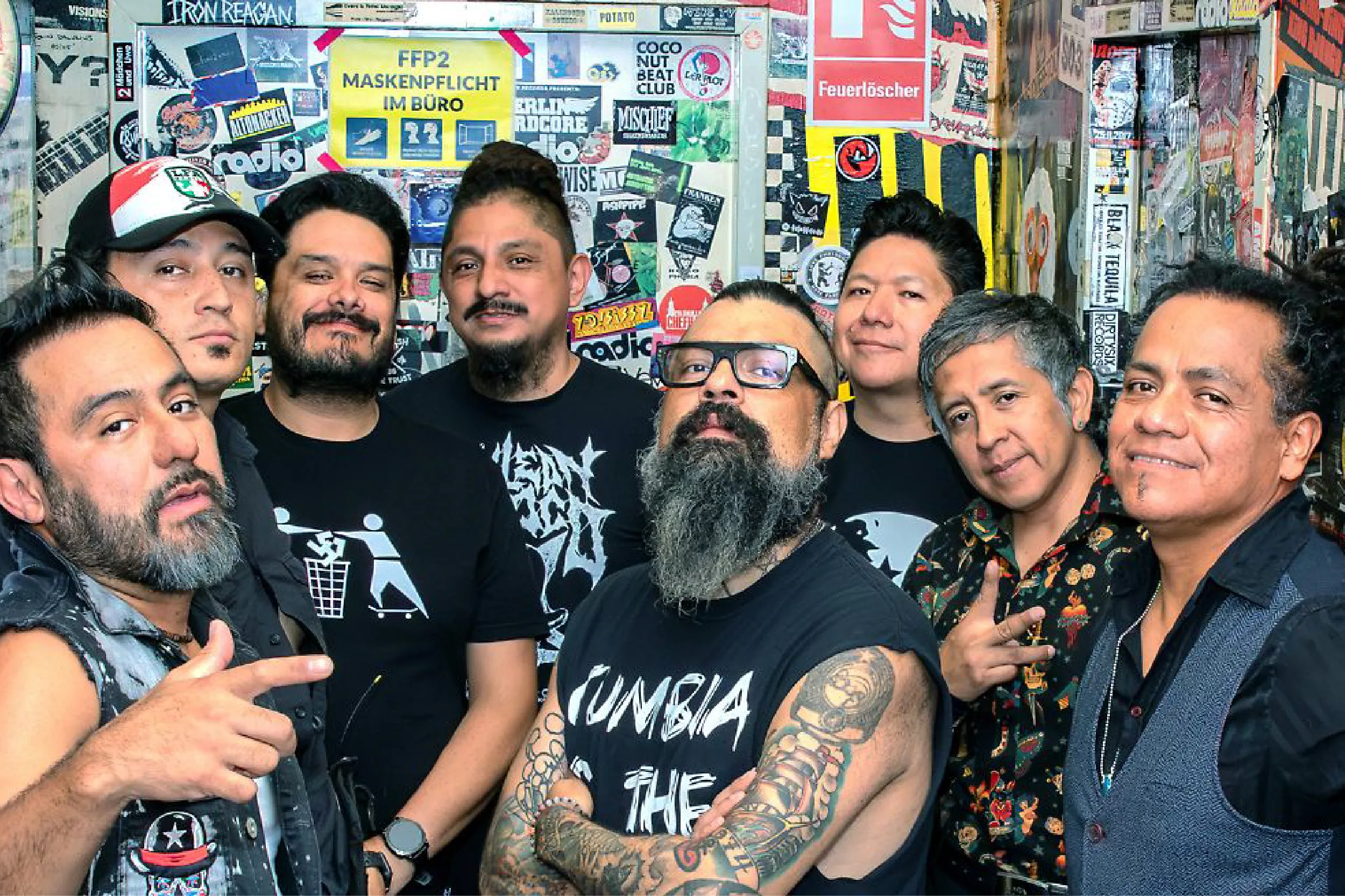 Group of friends posing for a photo in front of a wall covered with colorful stickers and posters on urban background.