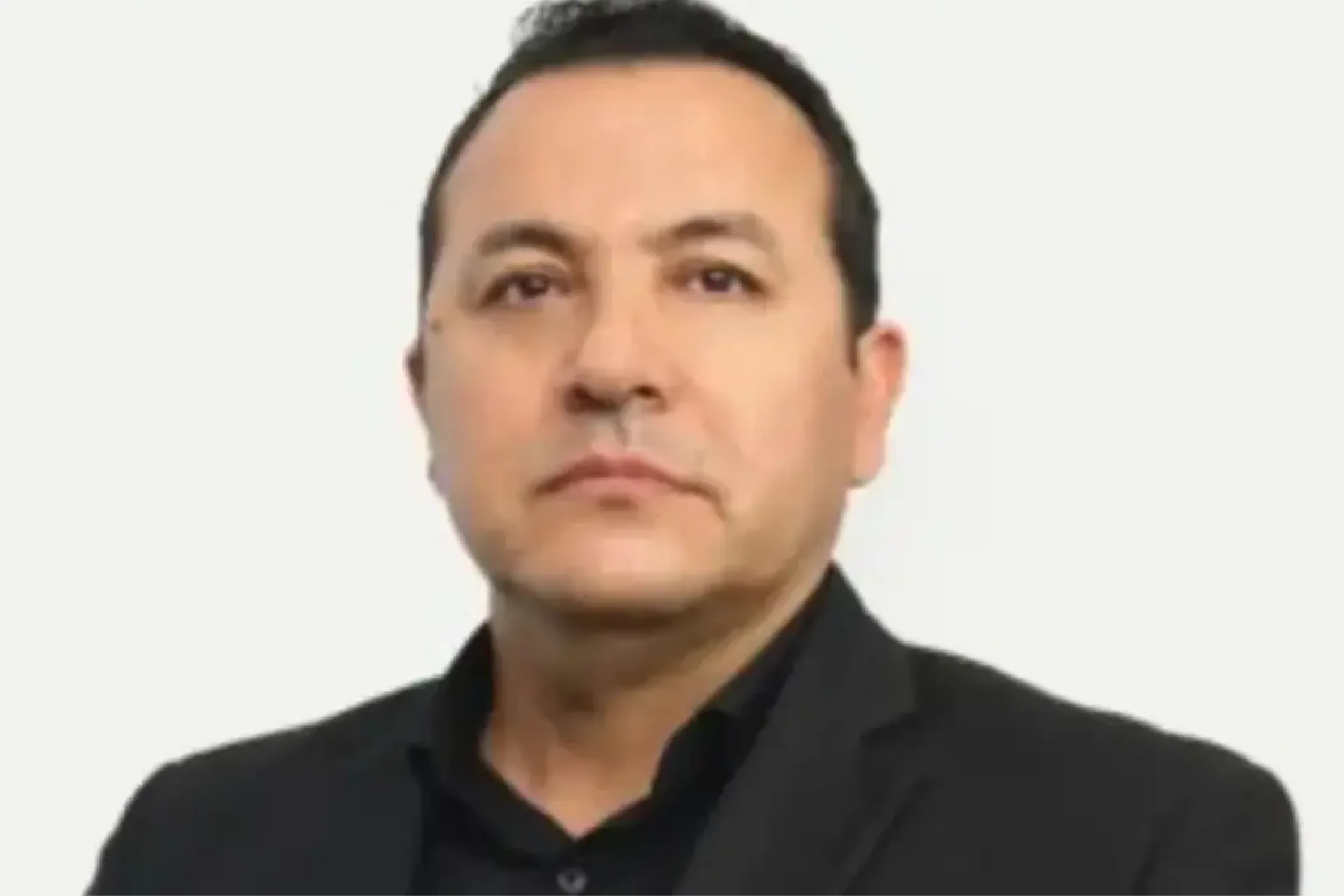 Portrait of a man in a black shirt against a light background, looking forward.