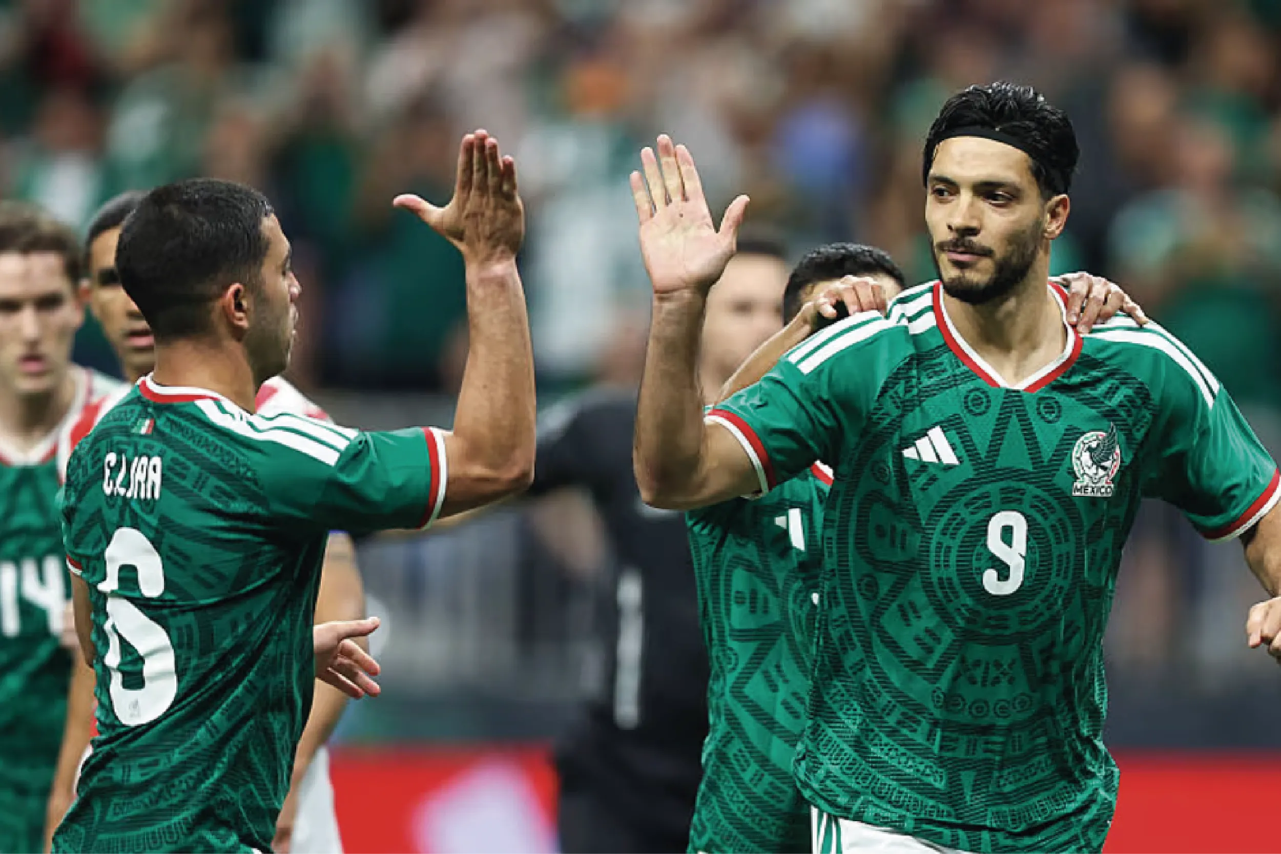 Mexican soccer players in green jerseys high-five each other on the field.