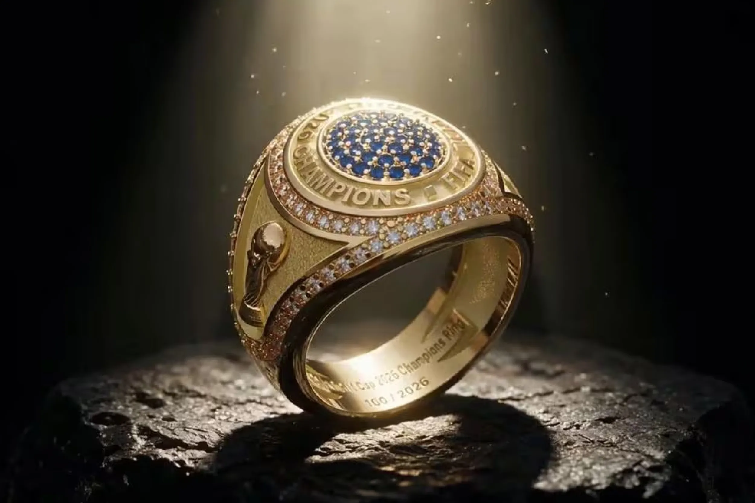 Close-up of a gold championship ring with a blue center, surrounded by diamonds and engraved text along the band.