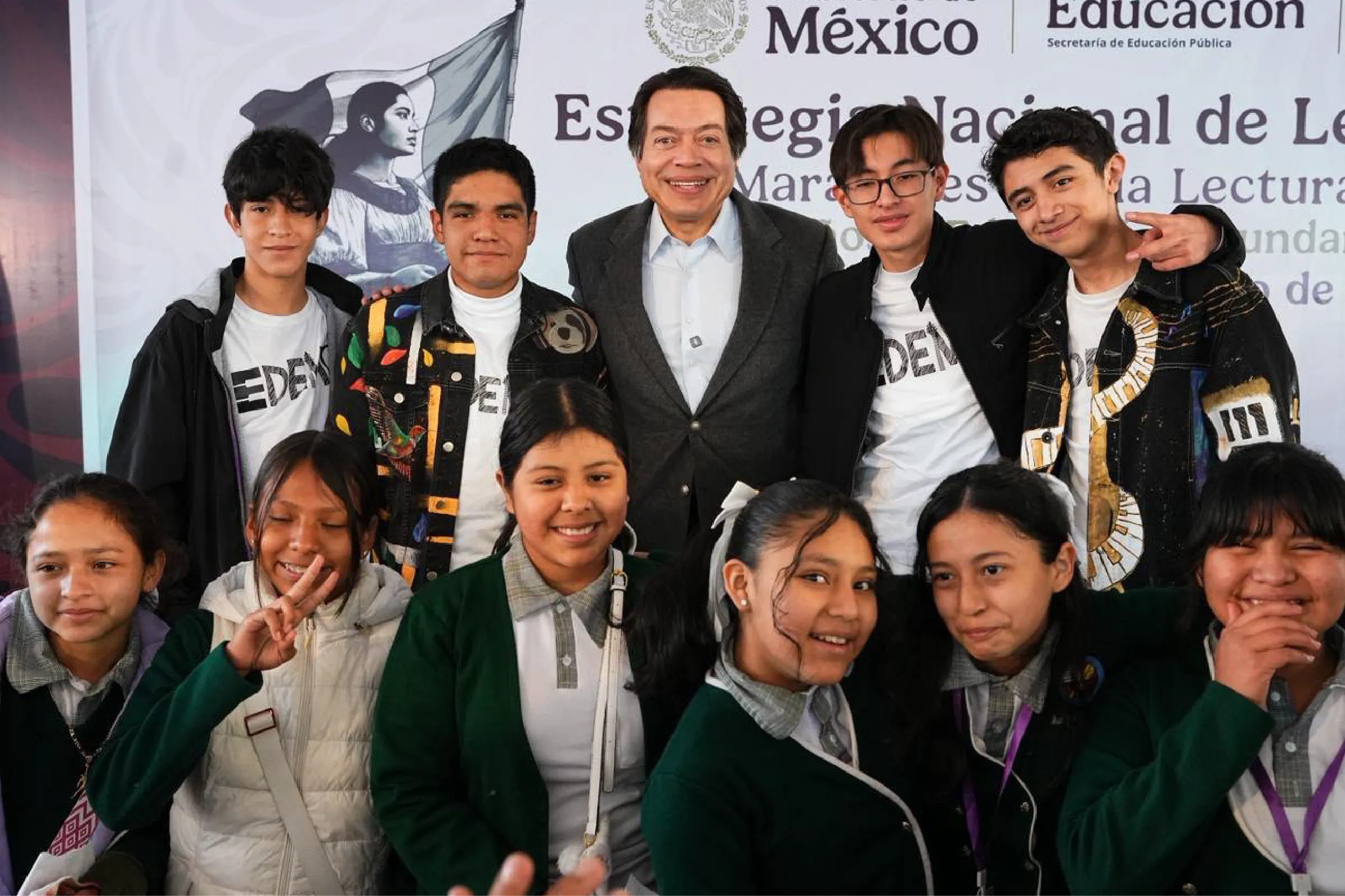 Group of smiling students posing with a man in a gray blazer at a school event.