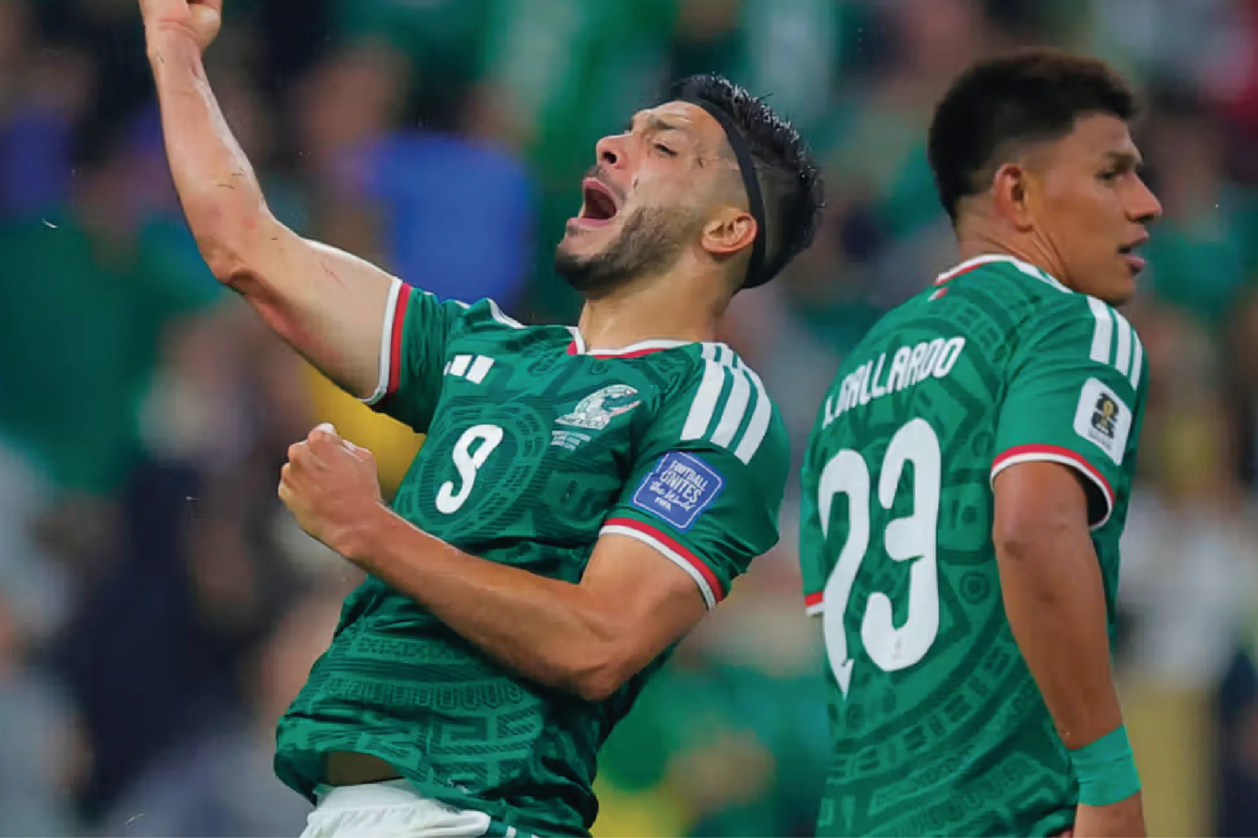 Two soccer players in green jerseys celebrate on the field, arms raised in triumph.