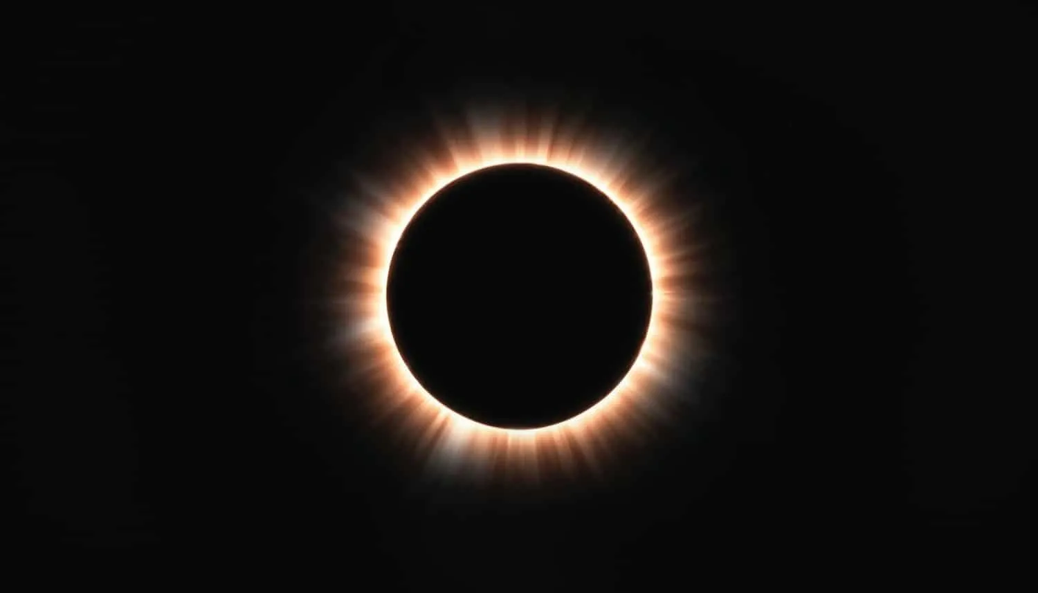 Solar eclipse: bright corona surrounding a dark circular disc against a black sky